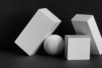 White geometric shapes on a black background. Platonic figures cube rectangle and sphere arranged...