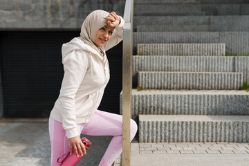 Middle eastern woman in hijab smiling while working out outdoors