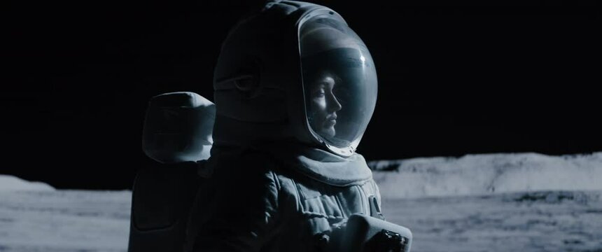 CU Portrait of Caucasian female lunar astronaut opens her visor while exploring Moon surface. Shot with 2x anamorphic lens