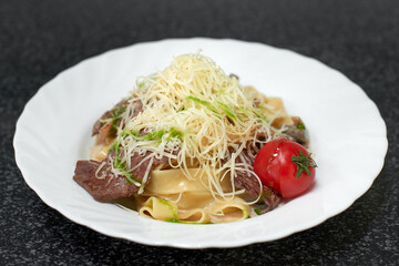 Pasta fettuccine cooked with meat, cheese and tomato in creamy sauce