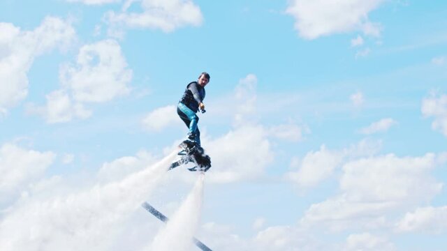 Sportive man flying in the air above the river on a flyboard