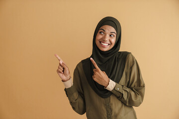 Black muslim woman in hijab smiling and pointing fingers aside