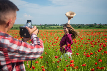 couple in love making photo. man with camera and woman in poppy field. summer flower meadow