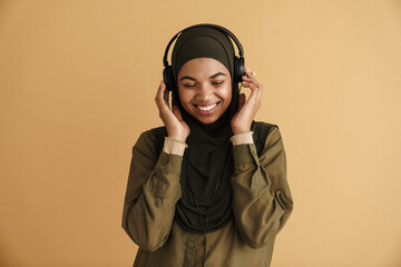 Black muslim woman in hijab listening music with headphones