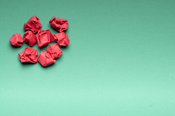Red crumpled paper balls in vague shape on green background