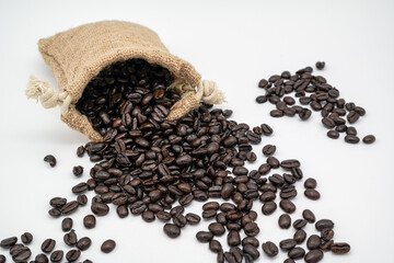 A group of fresh brown coffee beans spilled out of a coffee sack.