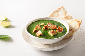 Palak Paneer with chapati on white background. Indian vegetarian cuisine made of spinach and paneer cheese. Close up.