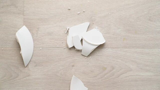 the white plate falls to the floor and breaks. View from above. 