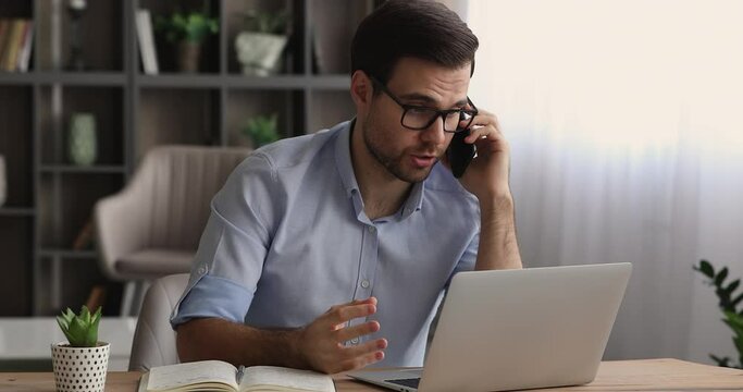 Male businessman sit at desk use laptop discuss project details with colleague by phone call having formal conversation provide help to client, distance communication, make order, modern tech concept