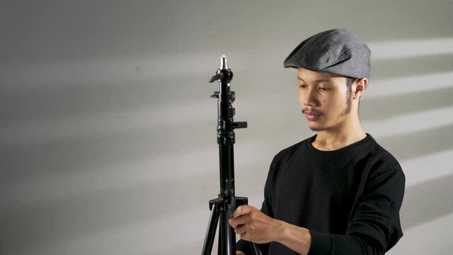 a young asian man preparing a camera tripod