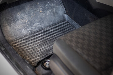 Car floor mats that are dirty with dust, dirt, sand and small rocks. which urgently needs to be cleaned to make the car look better.