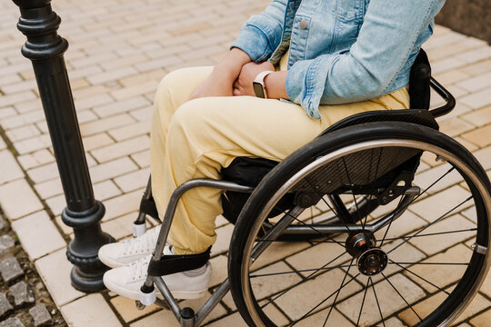 Cropped photo of woman sitting in wheelchair on city street