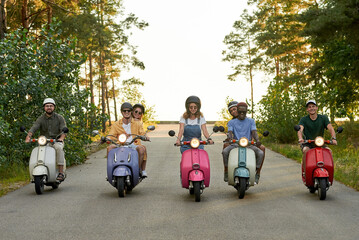 Happy young multiracial company riding colorful scooters © Svitlana