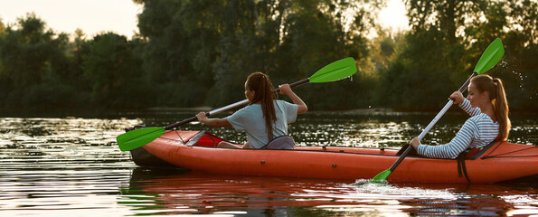 Two active young women, best friends kayaking in a lake surrounded by beautiful nature © Svitlana