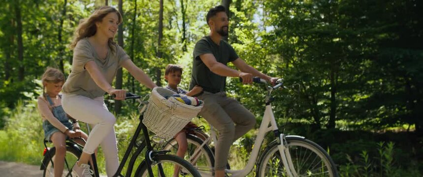 Video of playful family riding bikes in the woods. Shot with RED helium camera in 8K.