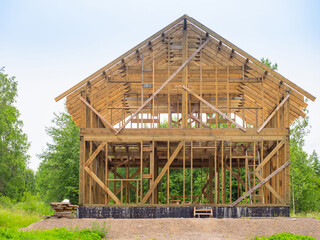 Frame of a wooden house with a triangular roof. Construction of a timber frame house. Process of...