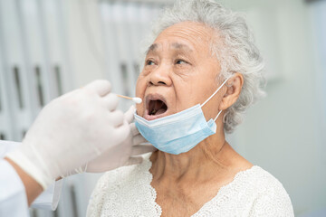 Doctor in pep suit taking a throat and nasal swab from senior asian woman patient to test covid-19...