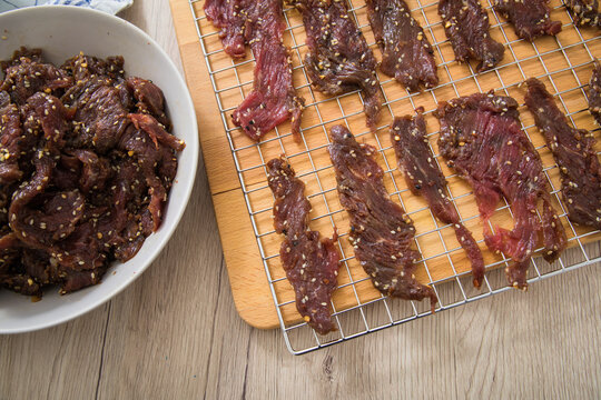 Asia Marinierte Rindfleisch Streifen Roh Für Hausgemachtes Beef Jerky Trockenfleisch Mit Sesam Und Chili Auf Edelstahl Trockengitter Für Dörrautomat In Küche Mit Holz Brett Hintergrund Hell