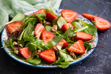 salad with strawberries, nuts on a concrete background