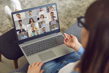Young business team manager sitting in comfortable chair at home with laptop computer on lap and...