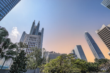 Low angle view of tall skyscrapers in central district of Hong Kong city center during sunset.