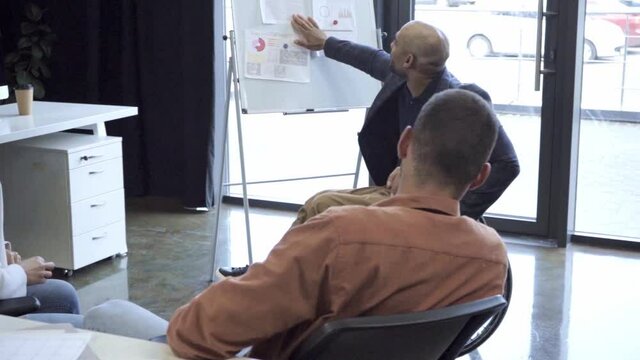 handicapped african american leader presenting charts and graphs to coworkers