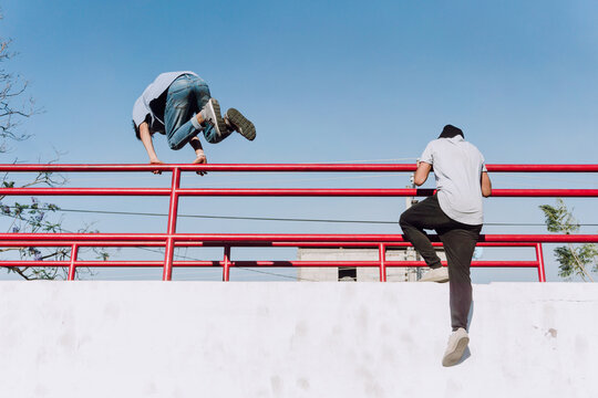 Anonymous men jumping over railing and showing parkour tricks