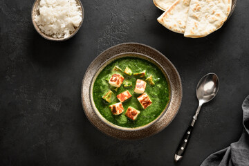 Palak Paneer served with chapati and basmati rice on a black background. Traditional Indian cuisine. Top view.