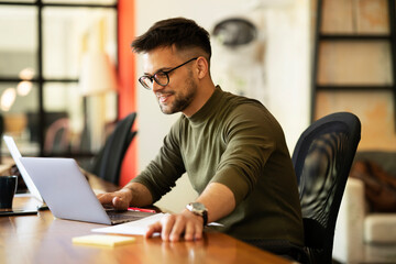 Fototapeta premium Young businessman using laptop in his office. Handsome man working on laptop