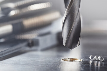 metal drill bit make holes in steel billet on industrial drilling machine. Metal work industry....