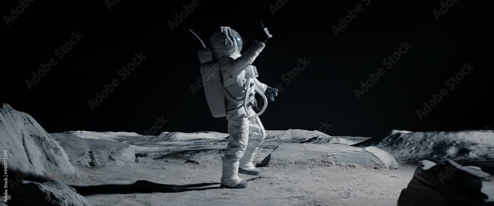 Wall mural astronaut searching for cellular or wi-fi signal while walking on moon surface. shot with 2x anamorp