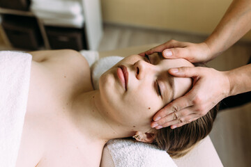 Fototapeta na wymiar Masseur doing massage on a woman's face at the spa.