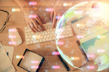 Multi exposure of man's hands typing over computer keyboard and world map hologram drawing. Top view. Technology concept.