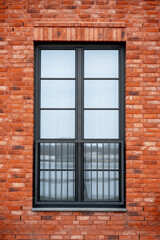 Part of the wall of a modern red brick residential building with a large window (898)