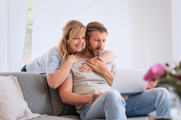 Happy couple relaxing together at home and using laptop