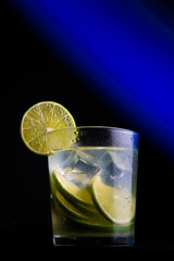 .Brazilian cocktail called Caipirinha. With lemon, ice and cachaça on a dark background with blue lights. Copy space