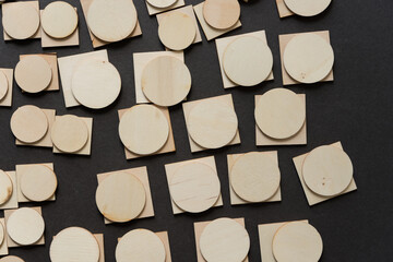 background composed of thin, untreated or natural round and square wooden shapes - loosely arranged on a dark gray ground - photographed in a top-down style 