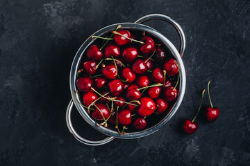 Cherry. Fresh organic sweet cherries in colander on dark stone background.