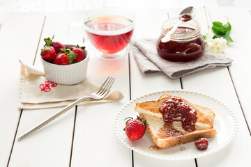Toasted bread slices with strawberry jam and a jar of jam