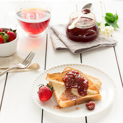 Toasted bread slices with strawberry jam and a jar of jam
