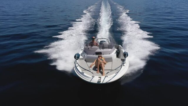 Aerial - Couple enjoying summer speeding on a motorboat, front view, close up
