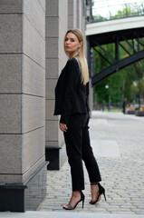 Obraz premium a blonde woman in a black business suit in the city.businesswoman on a walk