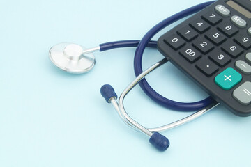 Stethoscope and calculator on blue background. Cost of medicine concept.	