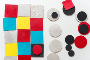 laser-cut plywood shapes hand painted in red, yellow, blue, pearl white and black loosely arranged...