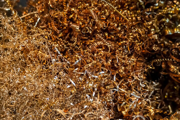 Close-up scene of brass materials scrap from turning process. The pile of lathe chips.
