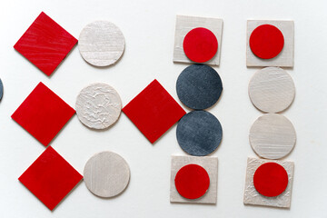 painted silver gray, red, and pearl white laser cut wooden plywood shapes, loosely arranged on a...