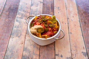 Neo recipe fusion of chickpea hummus replacing the cream cheese of a plate of nachos with guacamole inside a beautiful white bowl with handles and golden edge