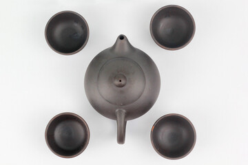 A Chinese black ceramic teapot and teacup isolated on a white background.