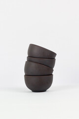 A Chinese black ceramic teapot and teacup isolated on a white background.