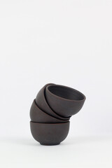 A Chinese black ceramic teapot and teacup isolated on a white background.